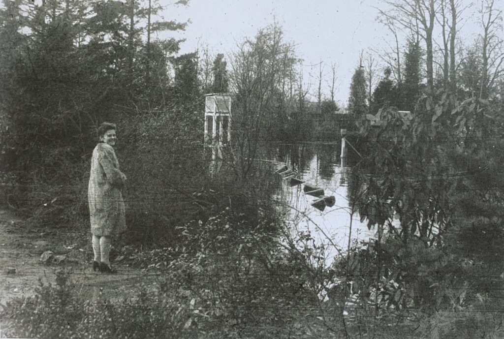 Leneke Thate poseert bij ondergelopen tuin Warnsveld met op achtergrond weerhuisje waar warmterecord is gemeten